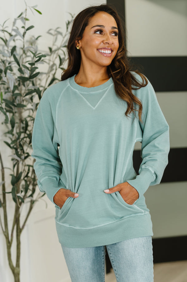 Woman wearing a light green sweater with a blurred indoor background