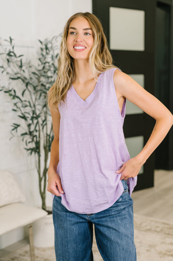Woman wearing a purple tank top and blue jeans indoors.