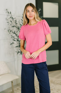 Woman wearing a pink top and navy pants in an indoor setting