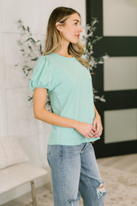 Woman wearing a light green top and jeans in an indoor setting