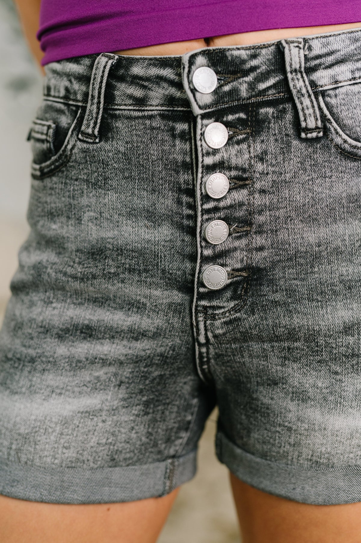 Gray denim shorts with button details on a blurred background
