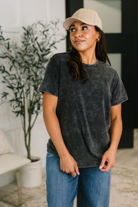 Woman wearing a black t-shirt and beige cap indoors
