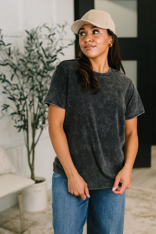 Woman wearing a black t-shirt and beige cap indoors