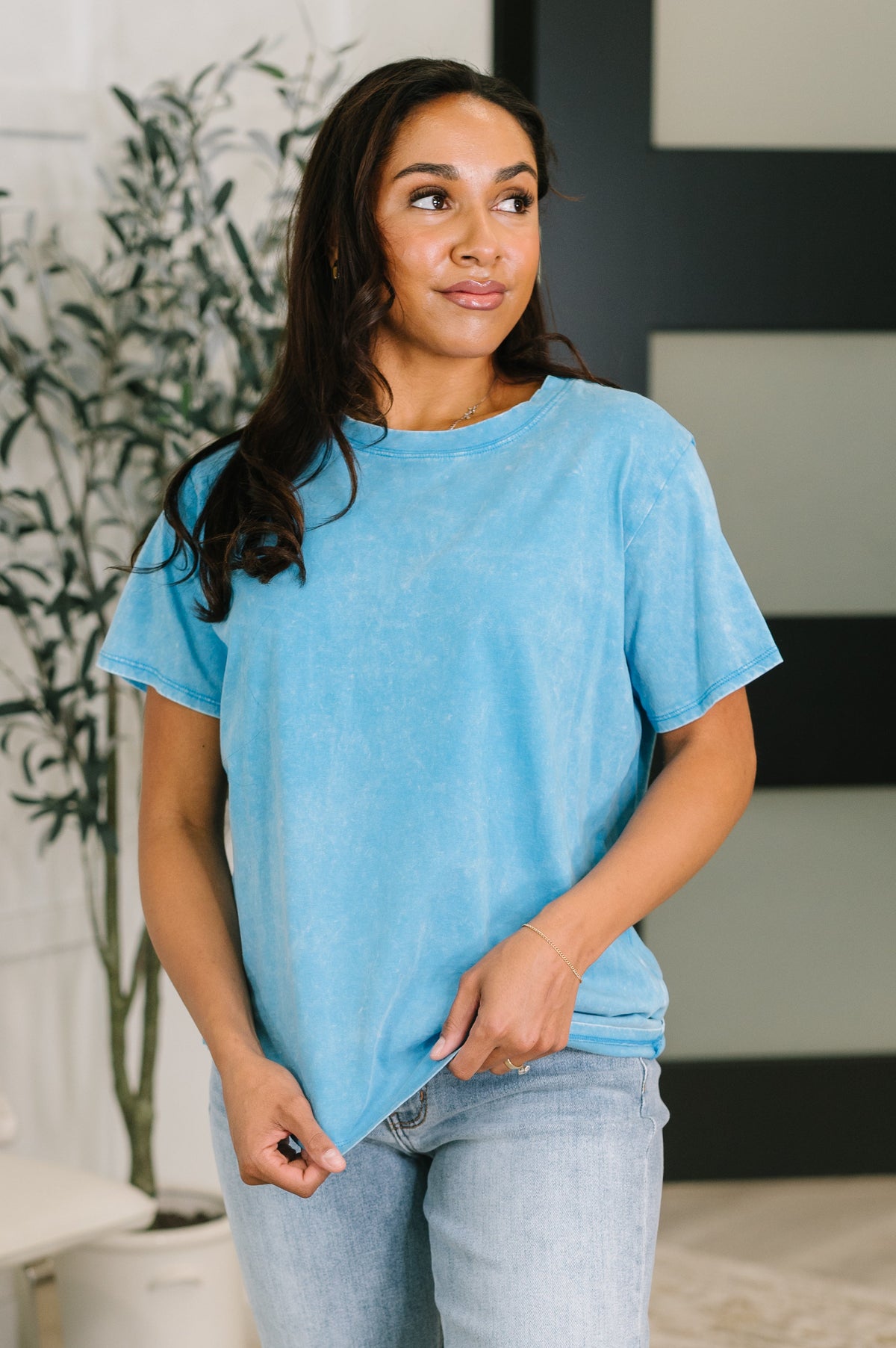 Woman wearing a blue t-shirt and jeans standing indoors.