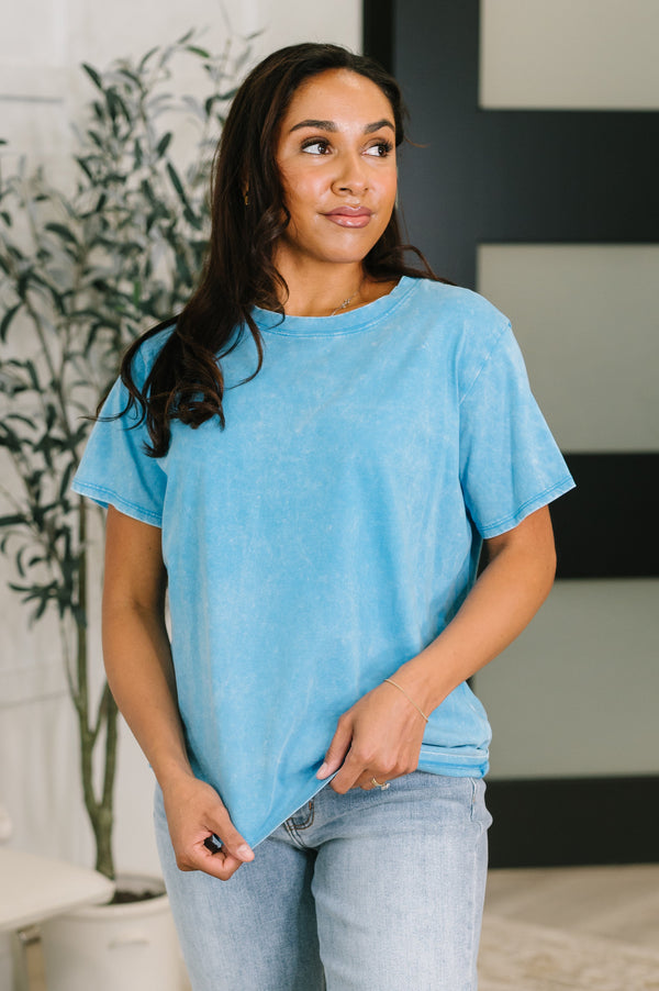 Woman wearing a blue t-shirt and jeans standing indoors.