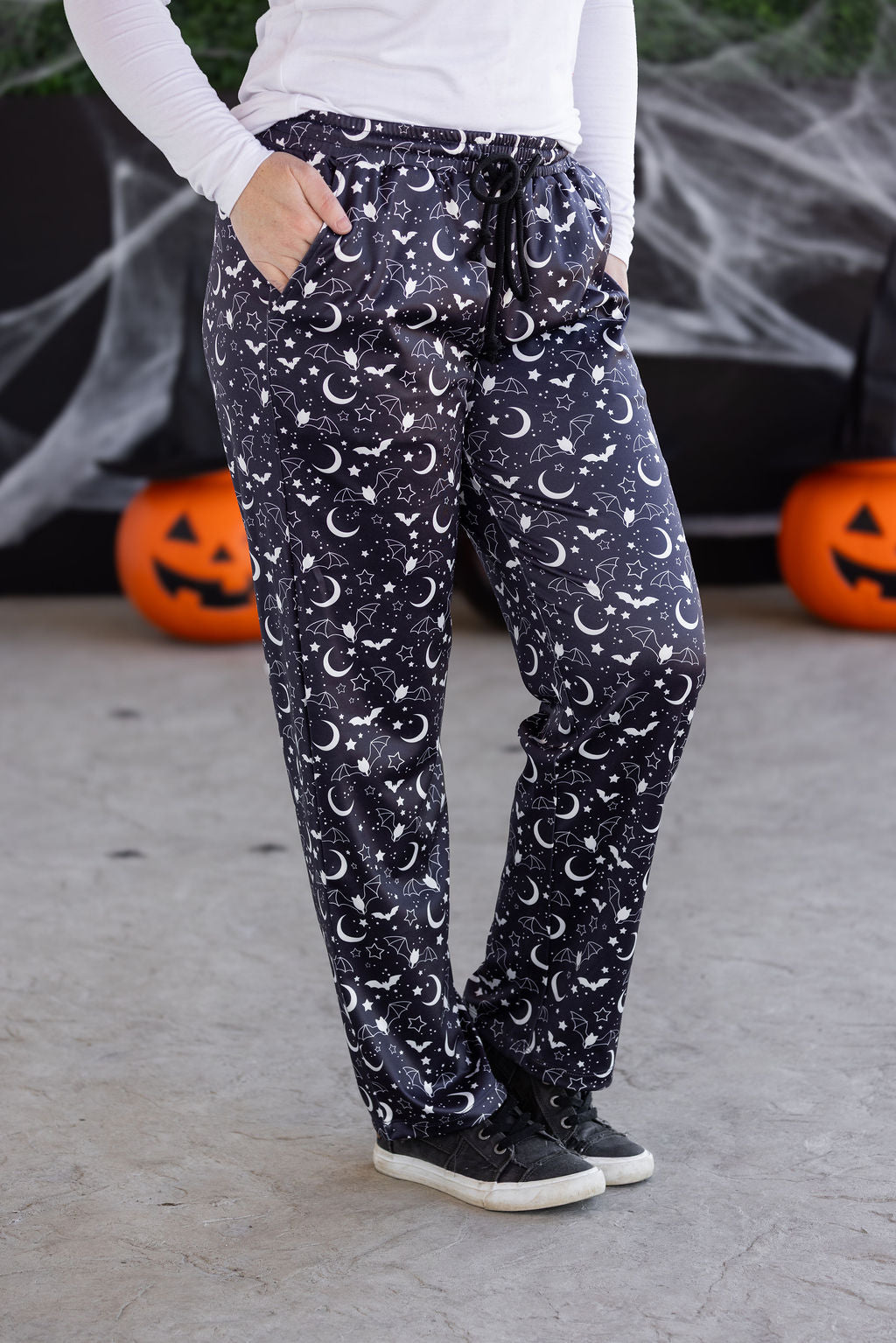 Person wearing dark pants with moon and star pattern in front of Halloween decorations.