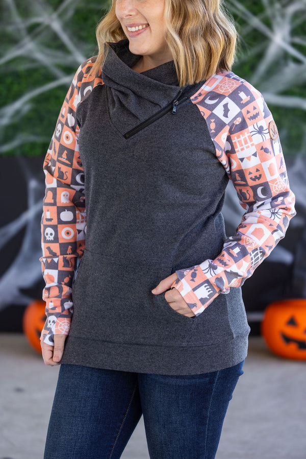 Woman wearing a dark gray hoodie with Halloween-themed sleeves in front of pumpkins.