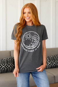 Woman wearing a dark gray t-shirt with a white graphic design and text, standing in a living room.