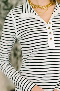 Black and white striped long-sleeve shirt with gold buttons worn by a person.