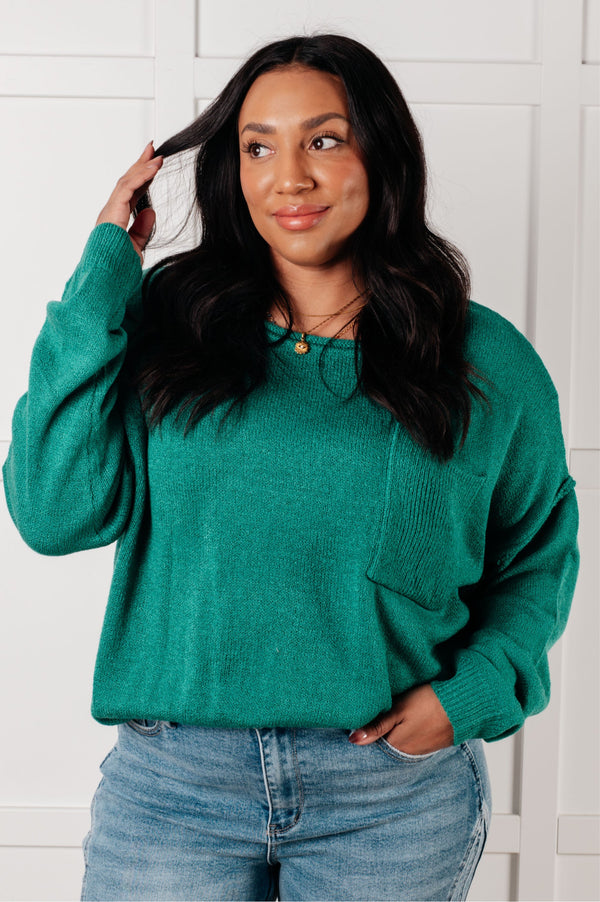 Woman wearing a teal sweater and jeans against a white wall