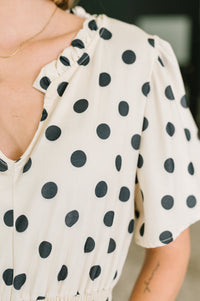 White blouse with black polka dots worn by a person, blurred background