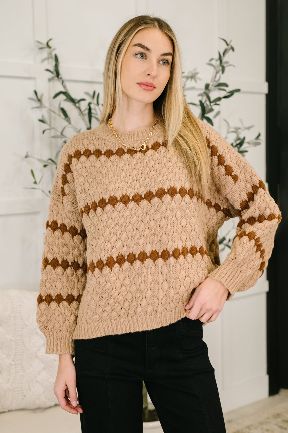 Woman wearing a beige sweater with brown stripes indoors