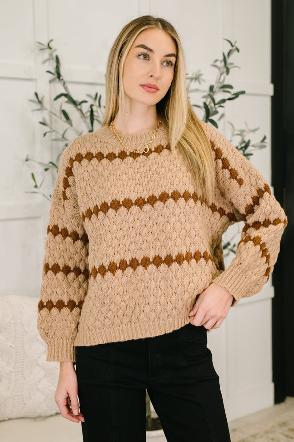 Woman wearing a beige sweater with brown stripes indoors