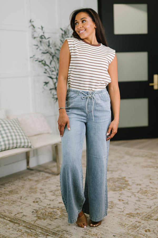 Woman wearing a striped shirt and blue jeans standing in a living room.