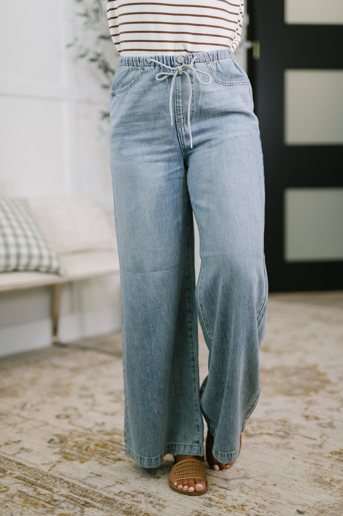 Person wearing light blue jeans and a striped shirt indoors.