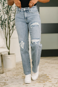 Person wearing light blue ripped jeans and white sneakers in an indoor setting.