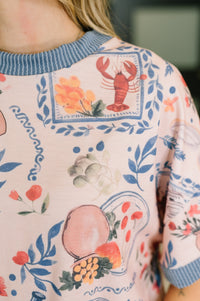 Close-up of a person wearing a patterned sweater with floral and lobster design.