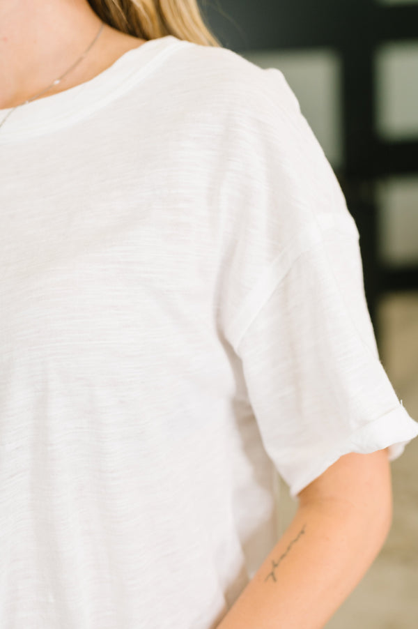 Person wearing a plain white t-shirt with a blurred background