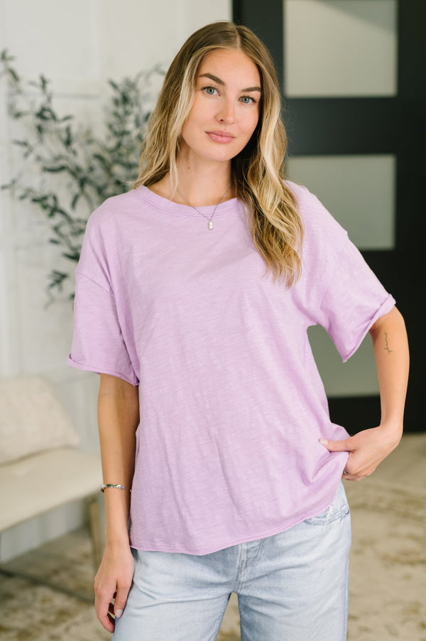 Woman wearing a light purple t-shirt and light blue jeans indoors.