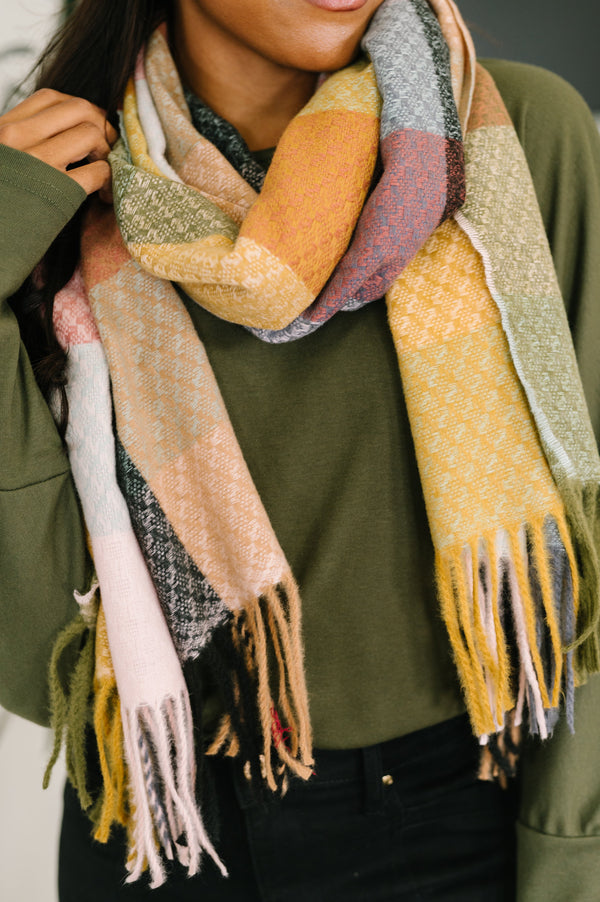 Person wearing a colorful scarf with fringes on a neutral background