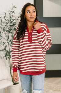 Woman wearing a red and white striped shirt with light blue jeans indoors.