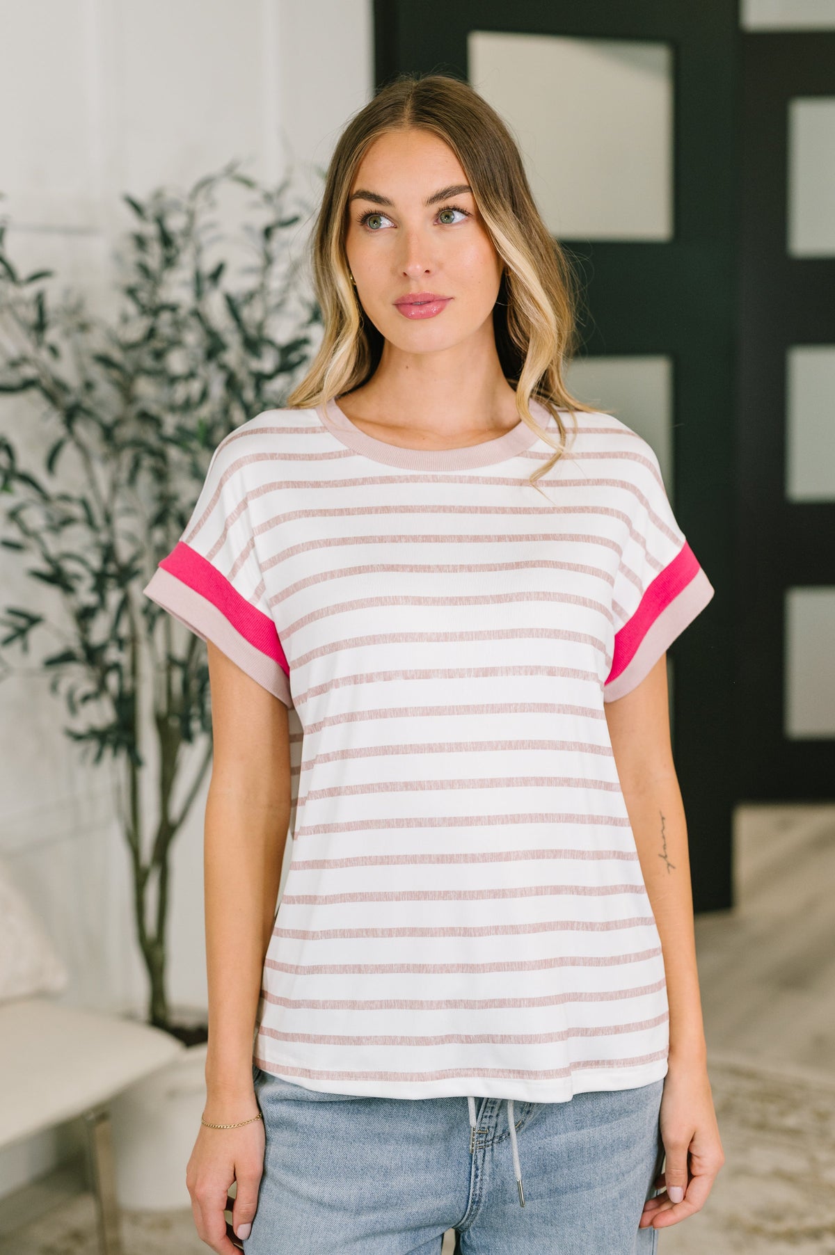 Woman wearing a striped shirt with pink accents in an indoor setting