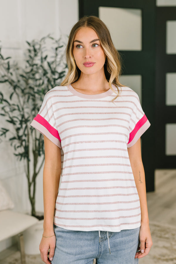 Woman wearing a striped shirt with pink accents in an indoor setting