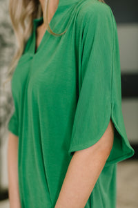 Green t-shirt worn by a person with a blurred background