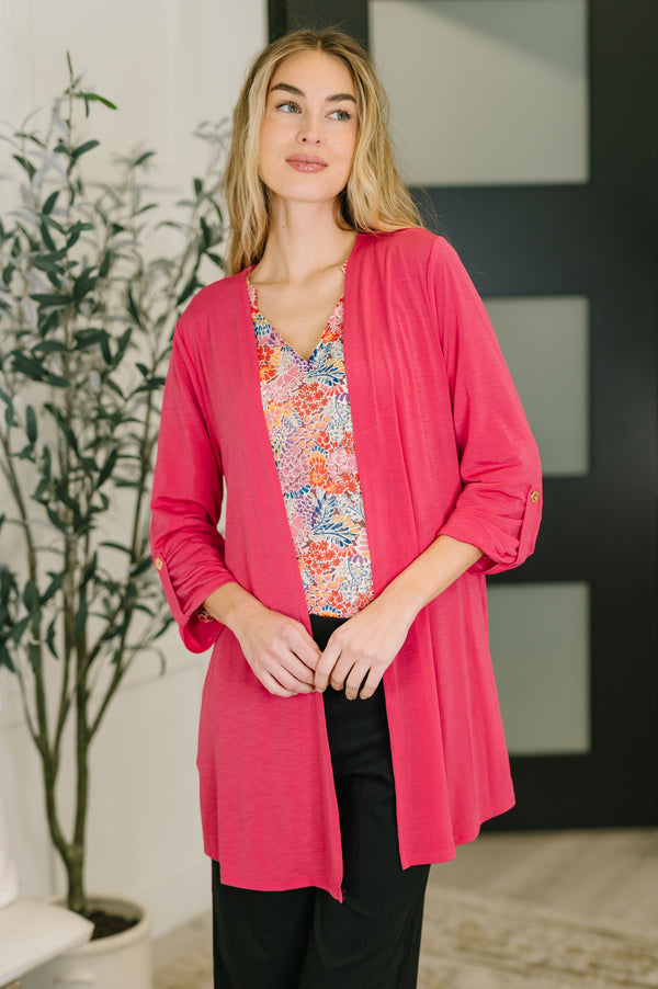 Woman wearing a pink cardigan over a floral top in an indoor setting.