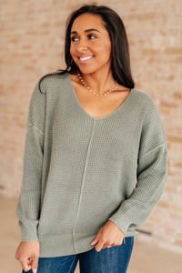 Woman wearing a green sweater against a beige wall
