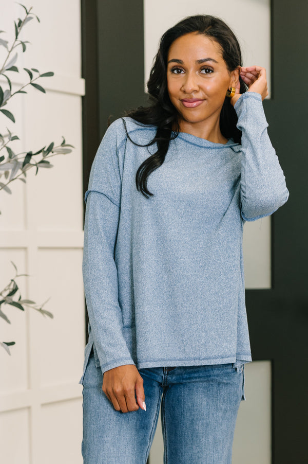 Woman wearing a blue sweater and jeans standing indoors.