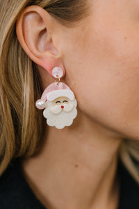 Close-up of a person wearing festive earrings with Santa Claus design.