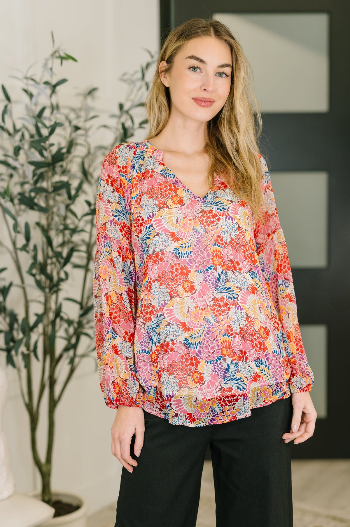 Woman wearing a colorful floral blouse in an indoor setting