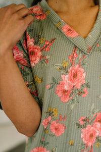 Person wearing a floral dress with pink flowers on a green background