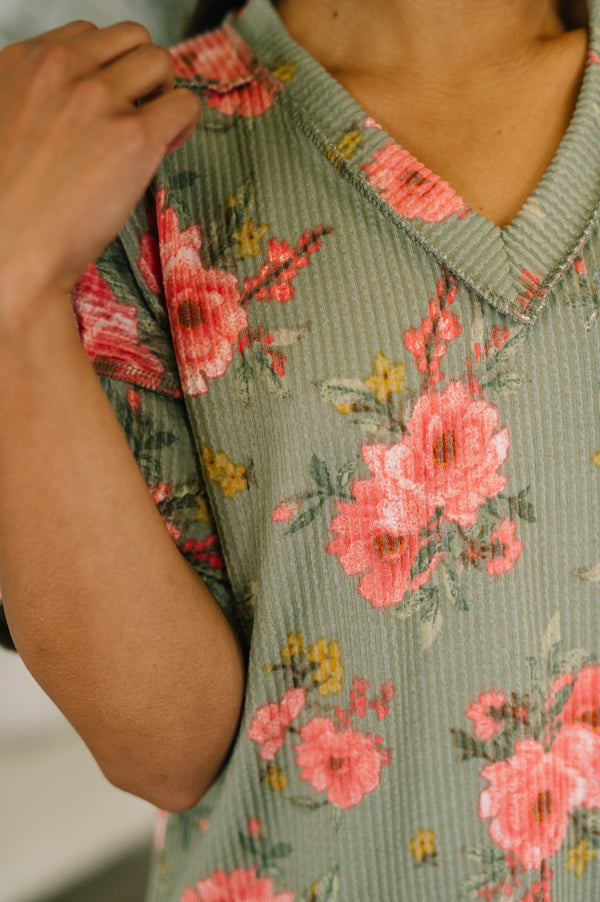 Person wearing a floral dress with pink flowers on a green background