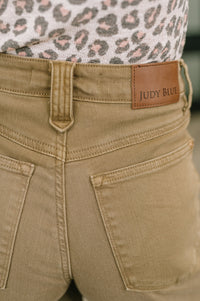 Close-up of beige pants with a brown label reading 'Judy Blue'.