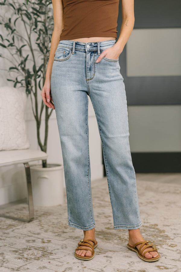 Person wearing light blue jeans and a brown top in an indoor setting.