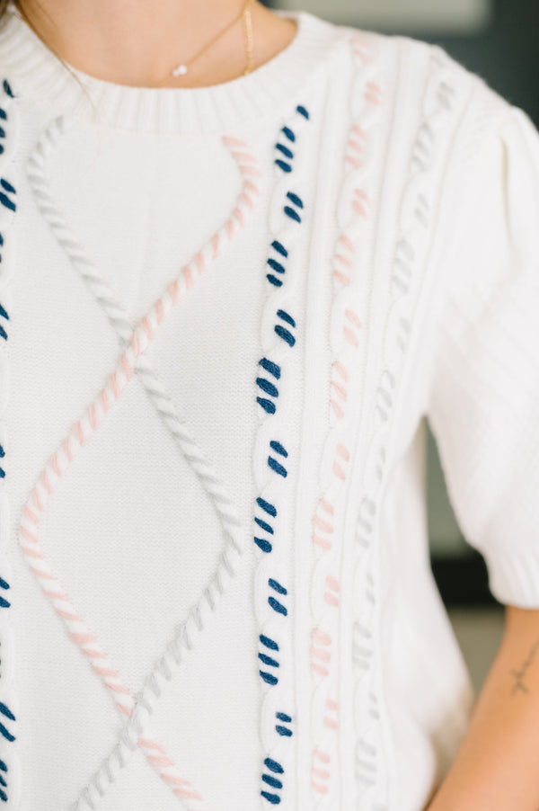 Close-up of a white sweater with blue and pink pattern
