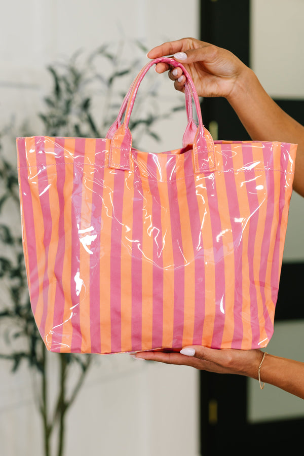 Hand holding a pink and orange striped clear bag.