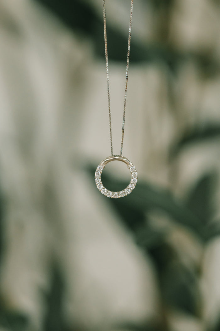 Necklace with a circular pendant against a blurred natural background