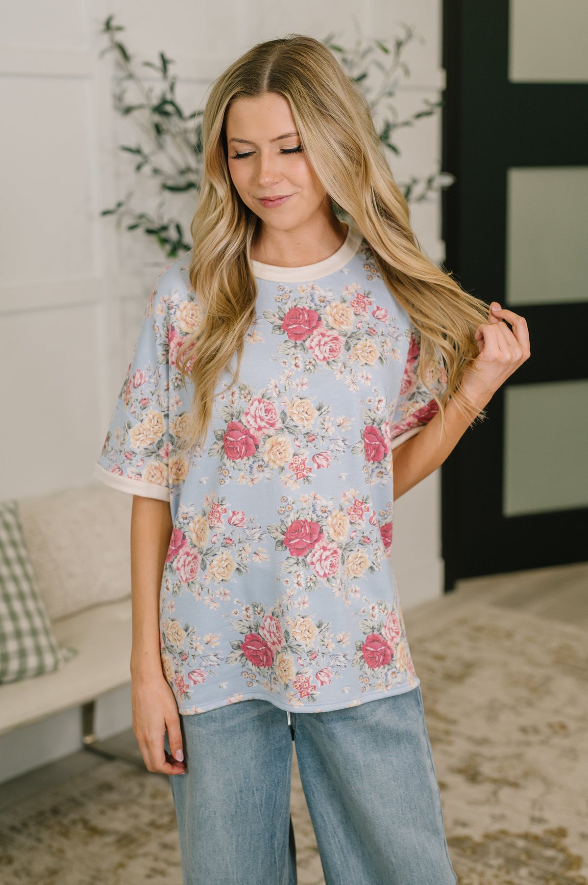 Woman wearing a floral blouse and jeans in a home setting