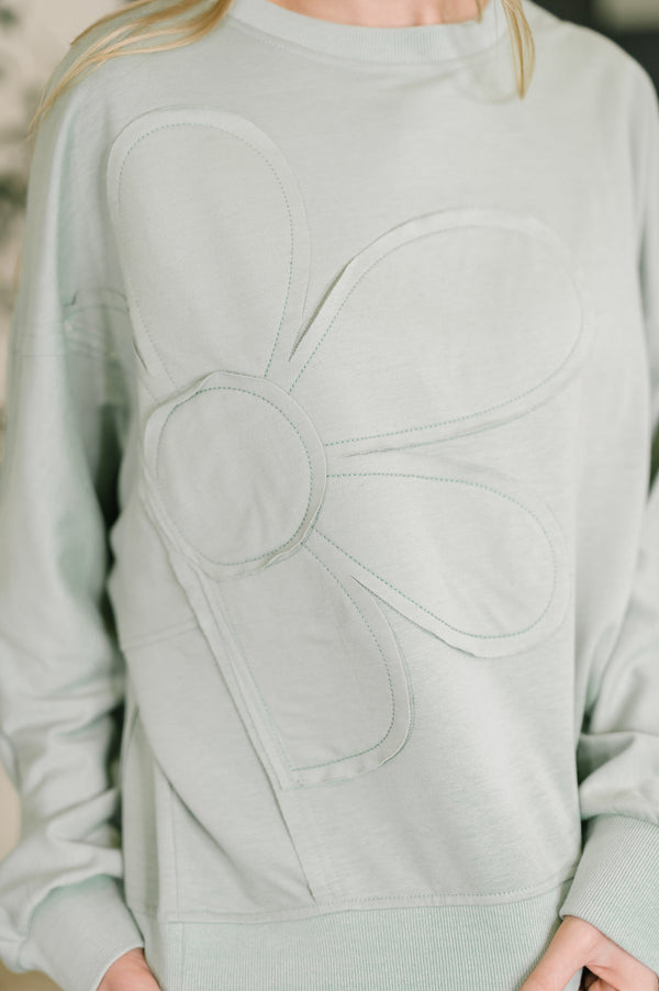 Light gray sweatshirt with floral design on a blurred background