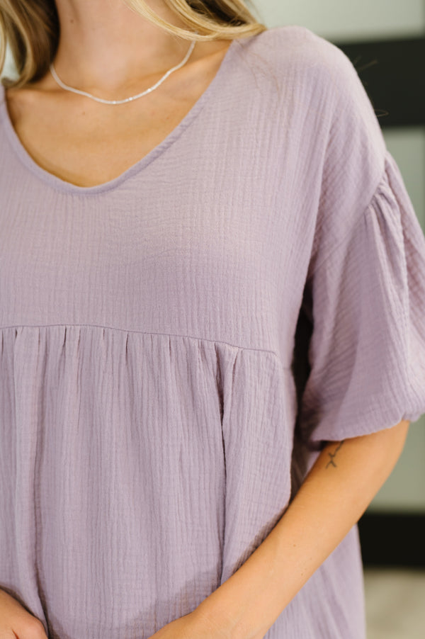 Close-up of a person wearing a light purple dress with a blurred background