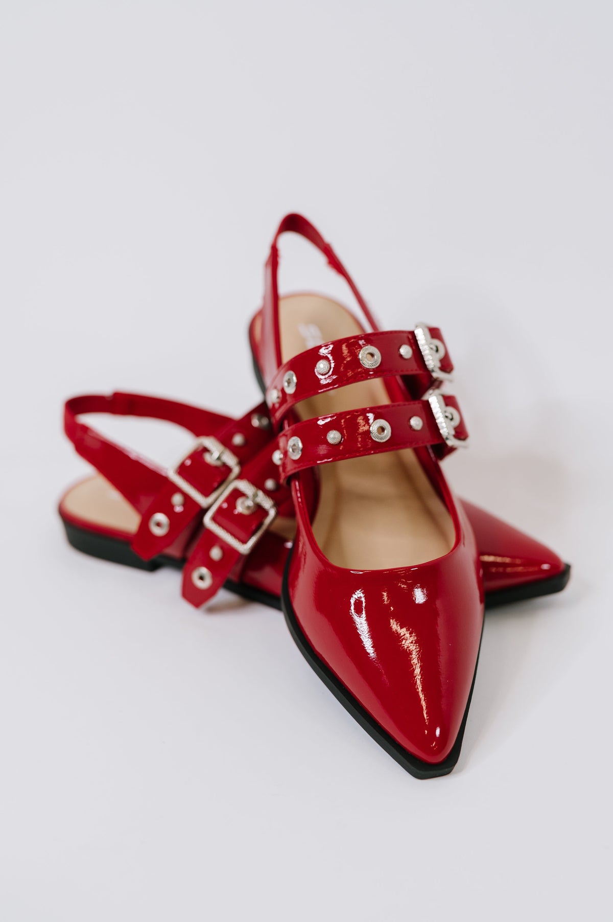 Red patent leather shoes with buckles on a white background