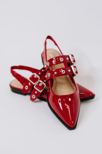 Red patent leather shoes with buckles on a white background