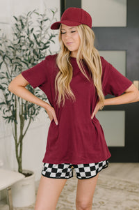 Woman wearing a maroon outfit with a cap indoors