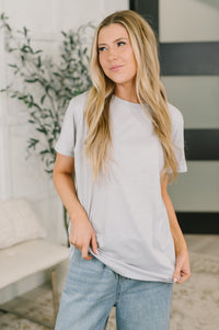 Woman wearing a light gray t-shirt and blue jeans indoors.
