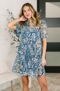 Woman wearing a blue paisley dress in an indoor setting
