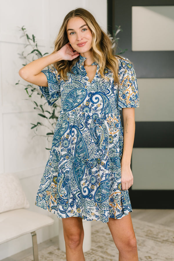 Woman wearing a blue paisley dress in an indoor setting