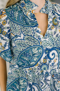 Close-up of a person wearing a patterned dress with blue and green paisley design.